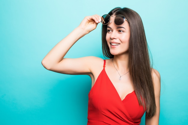 Retrato de joven bella mujer, elegante vestido rojo, tendencia de moda, con gafas de sol en la pared azul