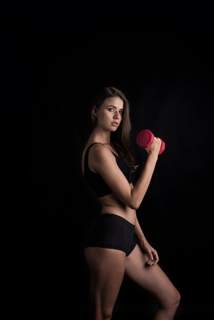 Retrato de joven bella mujer haciendo ejercicios físicos con pesas