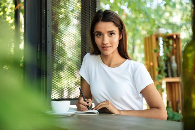 Retrato de una joven bella mujer haciendo notas en un libro de texto