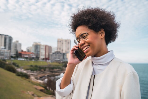 Retrato de joven bella mujer latina hablando por teléfono al aire libre. Concepto de comunicación.