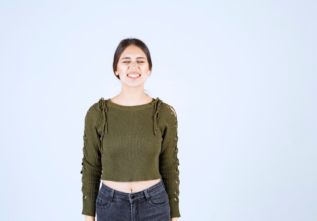 Foto gratuita retrato de una joven y bella mujer modelo de pie y posando sobre la pared blanca