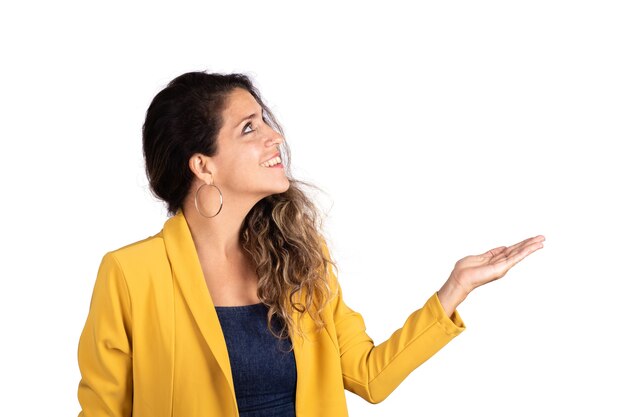 Retrato de joven bella mujer mostrando algo en estudio. Fondo blanco aislado.