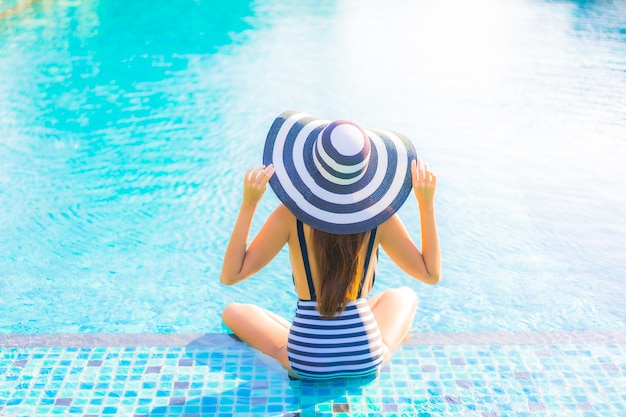 Foto gratuita retrato joven y bella mujer relajarse sonrisa ocio de vacaciones alrededor de la piscina en el hotel resort