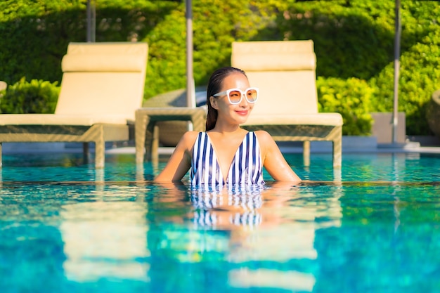 Retrato joven y bella mujer relajarse sonrisa ocio de vacaciones alrededor de la piscina en el hotel resort
