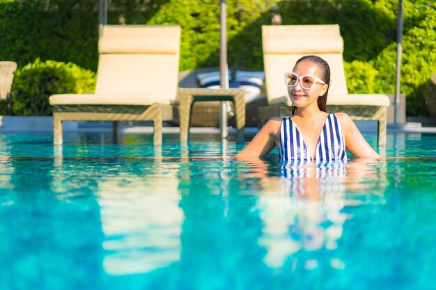 Retrato joven y bella mujer relajarse sonrisa ocio de vacaciones alrededor de la piscina en el hotel resort