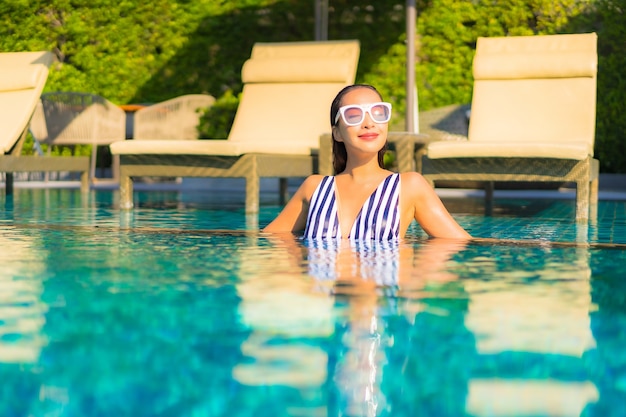 Retrato joven y bella mujer relajarse sonrisa ocio de vacaciones alrededor de la piscina en el hotel resort