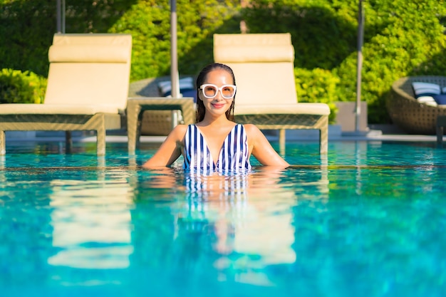 Retrato joven y bella mujer relajarse sonrisa ocio de vacaciones alrededor de la piscina en el hotel resort