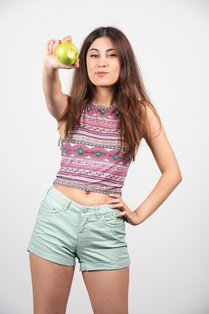 Retrato de joven bella mujer en ropa de verano mostrando una manzana.