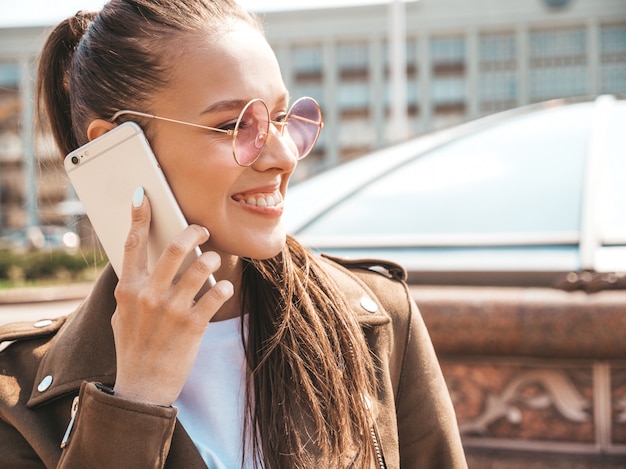 Retrato de joven bella mujer sonriente hablando por teléfono Chica de moda en ropa casual de verano Mujer divertida y positiva posando en la calle