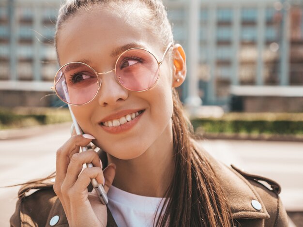 Retrato de joven bella mujer sonriente hablando por teléfono Chica de moda en ropa casual de verano Mujer divertida y positiva posando en la calle