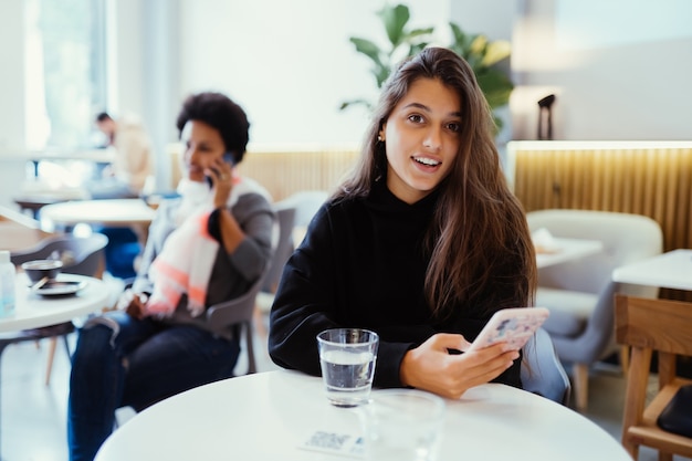 Retrato de una joven y bella mujer trabaja en una computadora portátil portátil, encantadora estudiante con net-book mientras está sentado en la cafetería