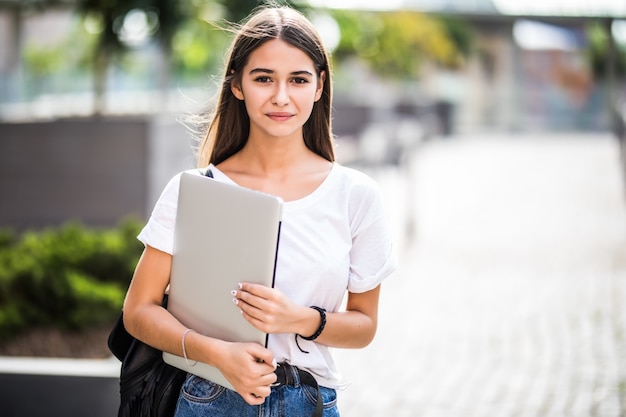 Retrato de joven blogger feliz con portátil moderno al aire libre