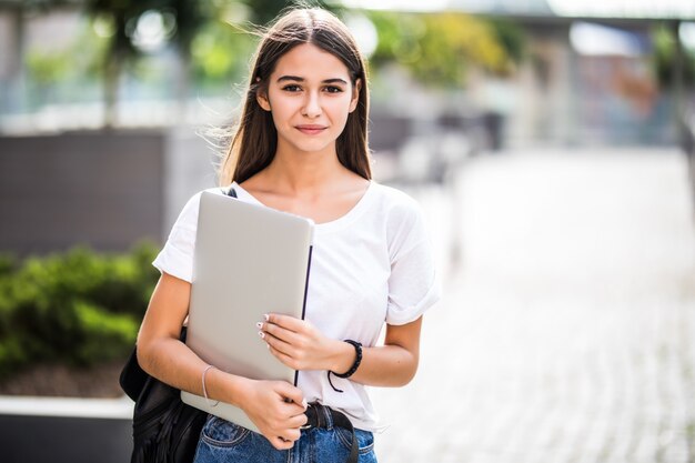 Retrato de joven blogger feliz con portátil moderno al aire libre