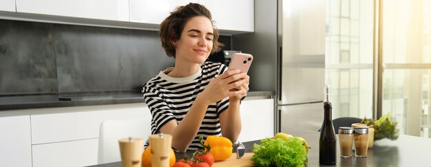 Foto gratuita retrato de una joven bloguera de comida que publica en las redes sociales una receta de ensalada vegana de pie en el