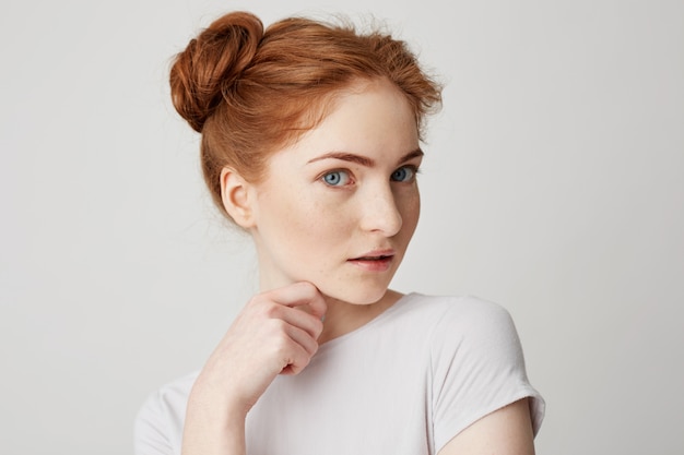Retrato de joven bonita con el pelo rojo tocando la barbilla.