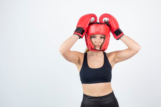 Retrato de joven boxeadora en guantes rojos y casco de lucha.