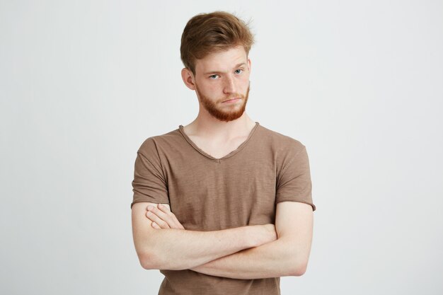 Retrato de joven brutal con barba con los brazos cruzados.