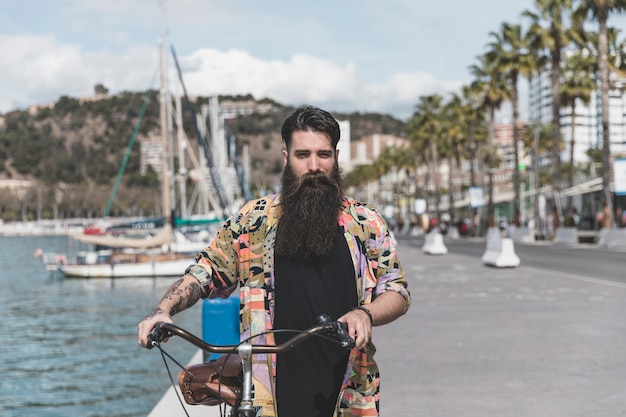 Foto gratuita retrato de un joven caminando en bicicleta cerca de la costa