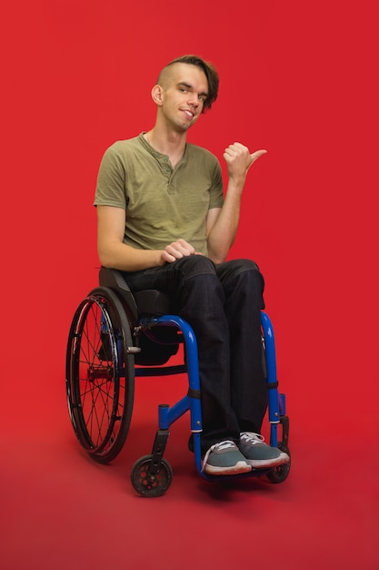 Foto gratuita retrato de joven caucásico en estudio rojo. concepto de emociones humanas