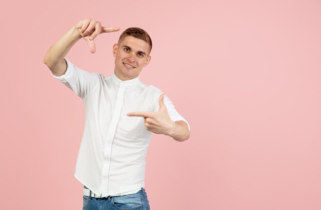 Retrato de un joven caucásico posando aislado sobre fondo rosa de estudio con espacio de copia para anuncios Concepto de emociones humanas