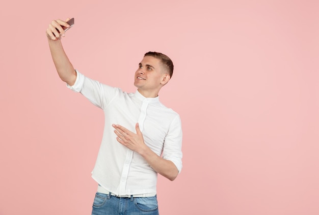 Retrato de un joven caucásico posando aislado sobre fondo rosa de estudio con espacio de copia para anuncios concepto de emociones humanas