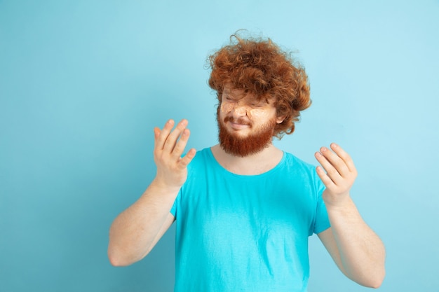 Retrato de joven caucásico en su día de belleza y rutina de cuidado de la piel. Modelo masculino con cabello rojo natural aplicando crema hidratante, aceites en la cara. Cuidado del cuerpo y la cara, concepto de belleza natural, masculina.