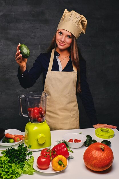Retrato de una joven cocinera tiene verduras.