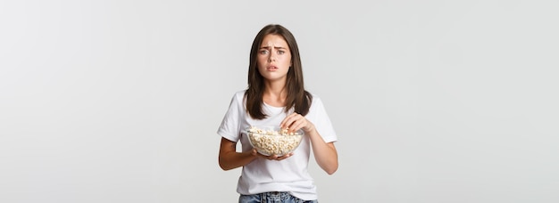 Foto gratuita retrato de una joven compasiva viendo una película conmovedora comiendo palomitas de maíz
