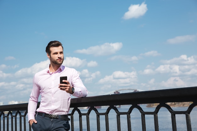 Retrato de joven confía en usar teléfono inteligente cerca del río