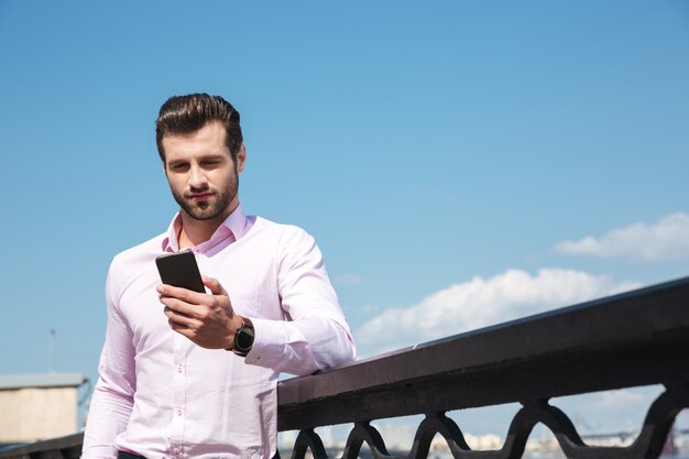 Retrato de joven confía en usar teléfono inteligente cerca del río