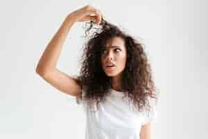 Foto gratuita retrato de una joven confundida mirando su cabello