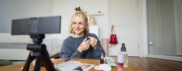 Foto gratuita retrato de una joven creadora de contenido y bloguera que graba un video en una cámara digital mostrando lápiz labial