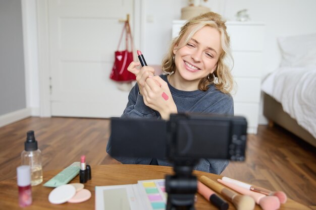 Retrato de una joven creadora de contenidos creativos en las redes sociales que muestra muestras de lápiz labial en su mano