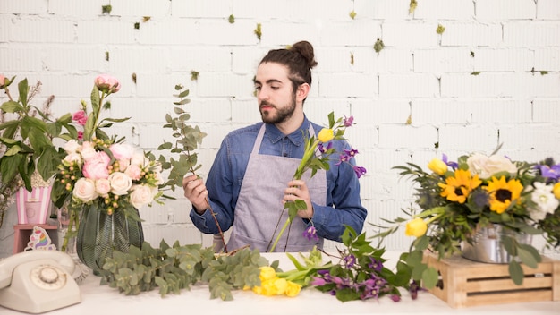 Retrato de un joven creando el ramo de flores en la floristería.