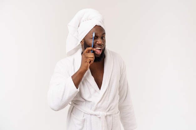 Retrato de un joven darkanm feliz cepillándose los dientes con pasta de dientes negra sobre un fondo blanco