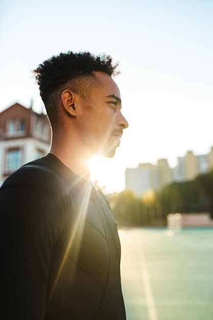 Retrato de un joven deportista afroamericano pensativo haciendo ejercicio en el estadio de la ciudad