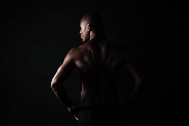 Retrato de joven deportista afroamericano, retrocediendo, mirando a un lado