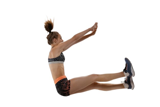 Retrato de joven deportista en entrenamiento deportivo saltando aislado sobre fondo blanco de estudio