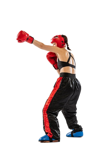 Retrato de joven deportista entrenando kickboxing en uniforme especial aislado sobre fondo blanco de estudio