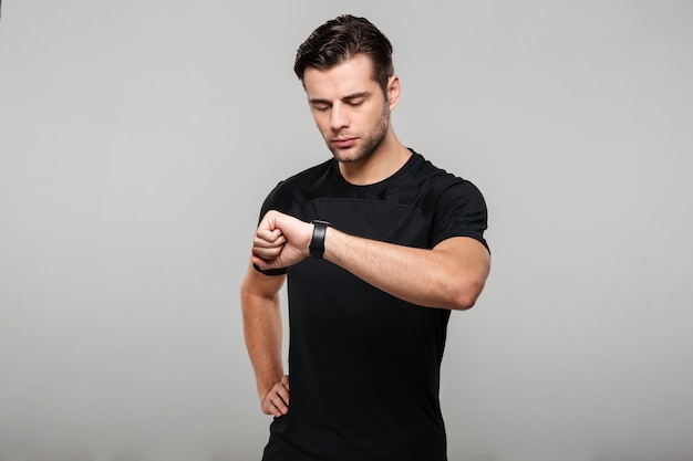 Retrato de un joven deportista mirando su reloj de pulsera