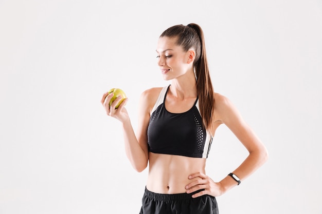 Retrato de una joven deportista sonriente con manzana verde