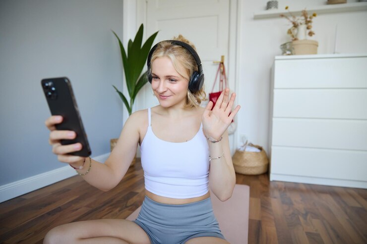 Foto gratuito retrato de una joven deportiva con auriculares graba video en su teléfono inteligente en transmisión en vivo y