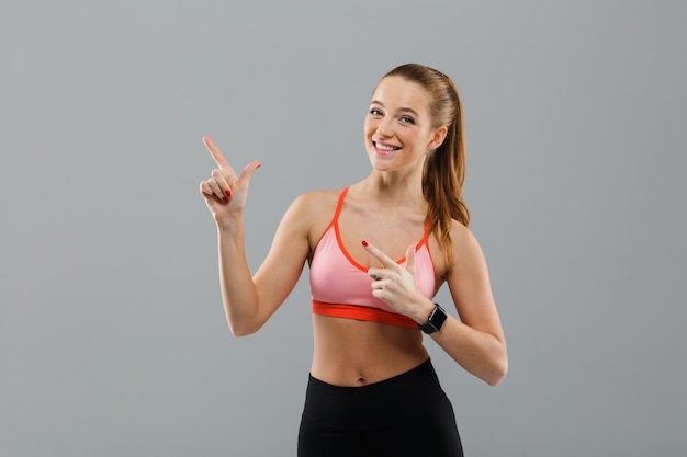 Foto gratuita retrato de una joven deportiva feliz señalando