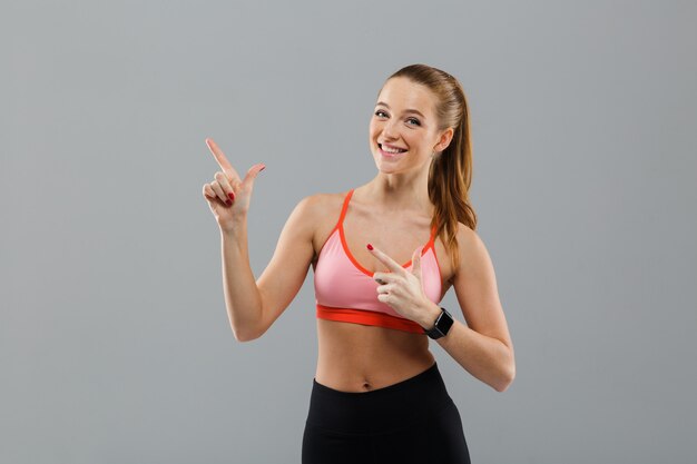 Retrato de una joven deportiva feliz señalando