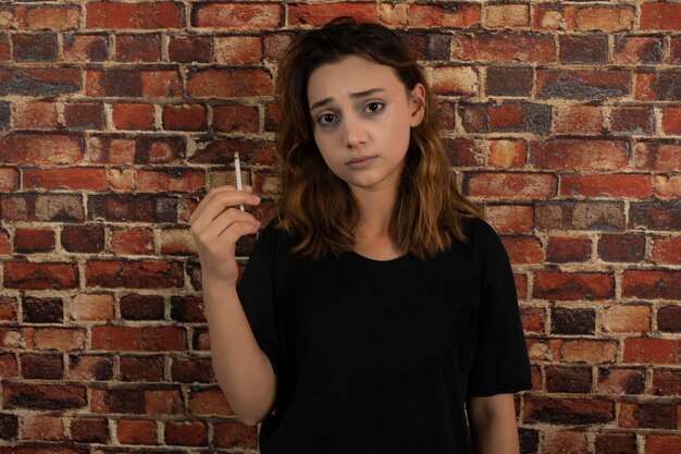 Retrato de una joven deprimida sosteniendo un cigarrillo. foto de alta calidad