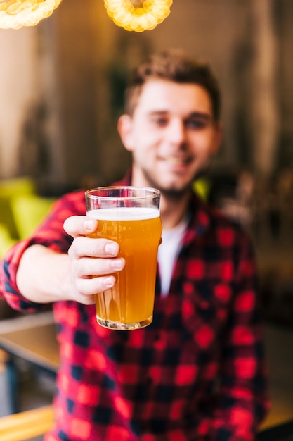 Retrato de un joven desenfocado sosteniendo un vaso de cerveza