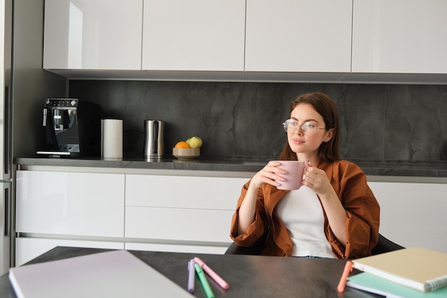 Foto gratuita retrato de una joven disfrutando de una taza de café en paz sentada en casa sosteniendo una taza con té de hierbas