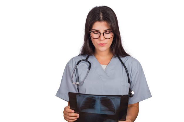 Retrato de joven doctora con estetoscopio y mirando una gammagrafía ósea en estudio. Concepto médico y sanitario.