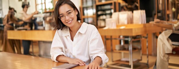 Retrato de una joven y elegante mujer de negocios en un café sentada con un cuaderno tomando notas trabajando en