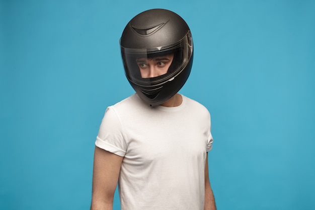 Retrato de joven elegante vestido con camiseta blanca y casco de moto posando